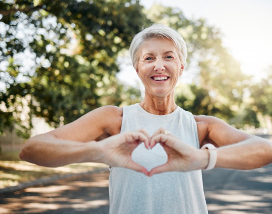 Lady smiles while making shape of heart with her hands